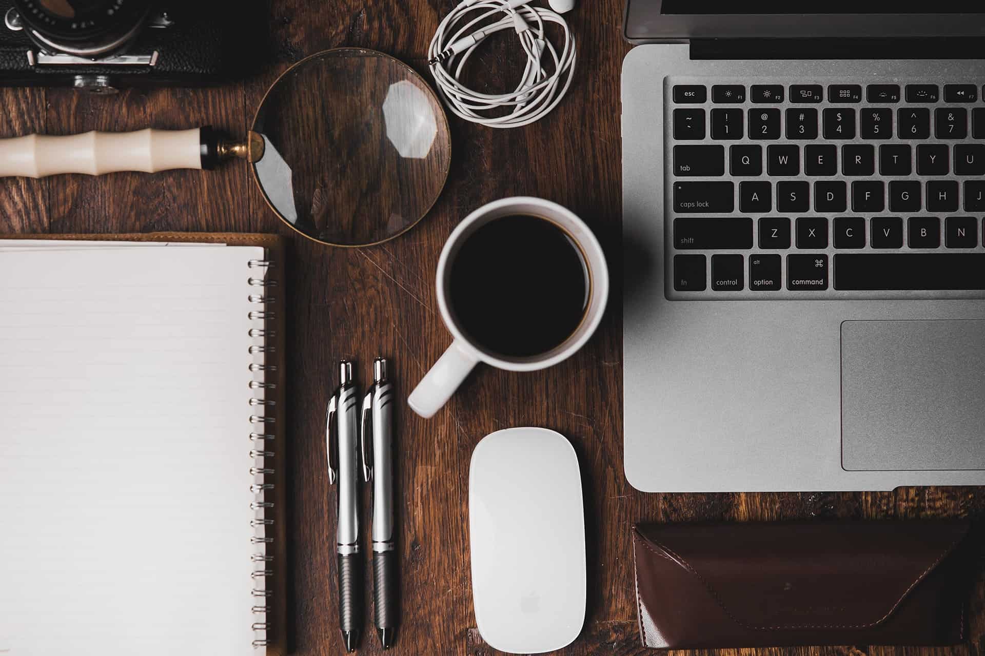 Styled desk workspace with a laptop, a cup of coffee, and stacks of folders.