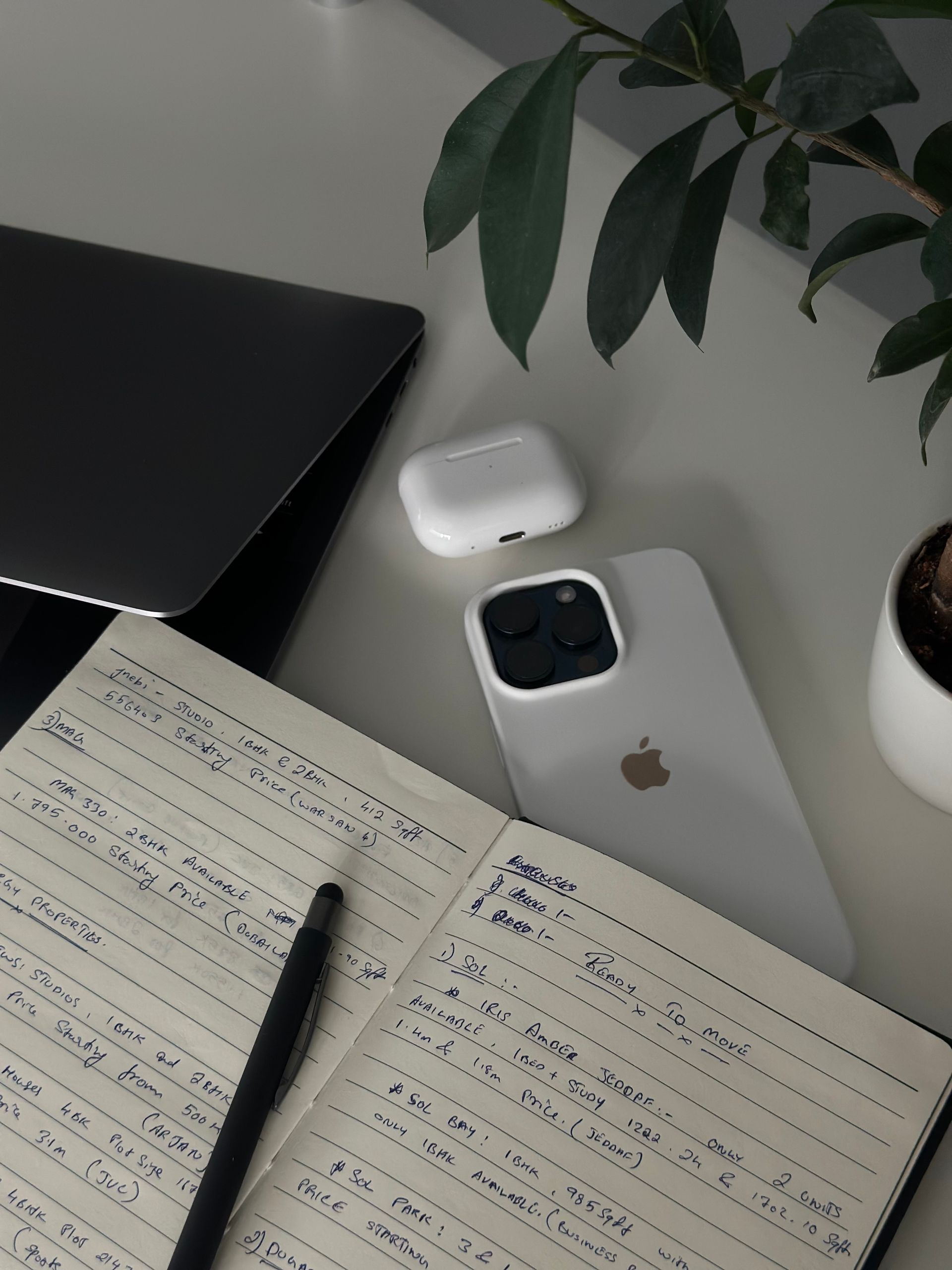 Sleek workspace with a laptop, digital devices, and handwritten notes on a desk.