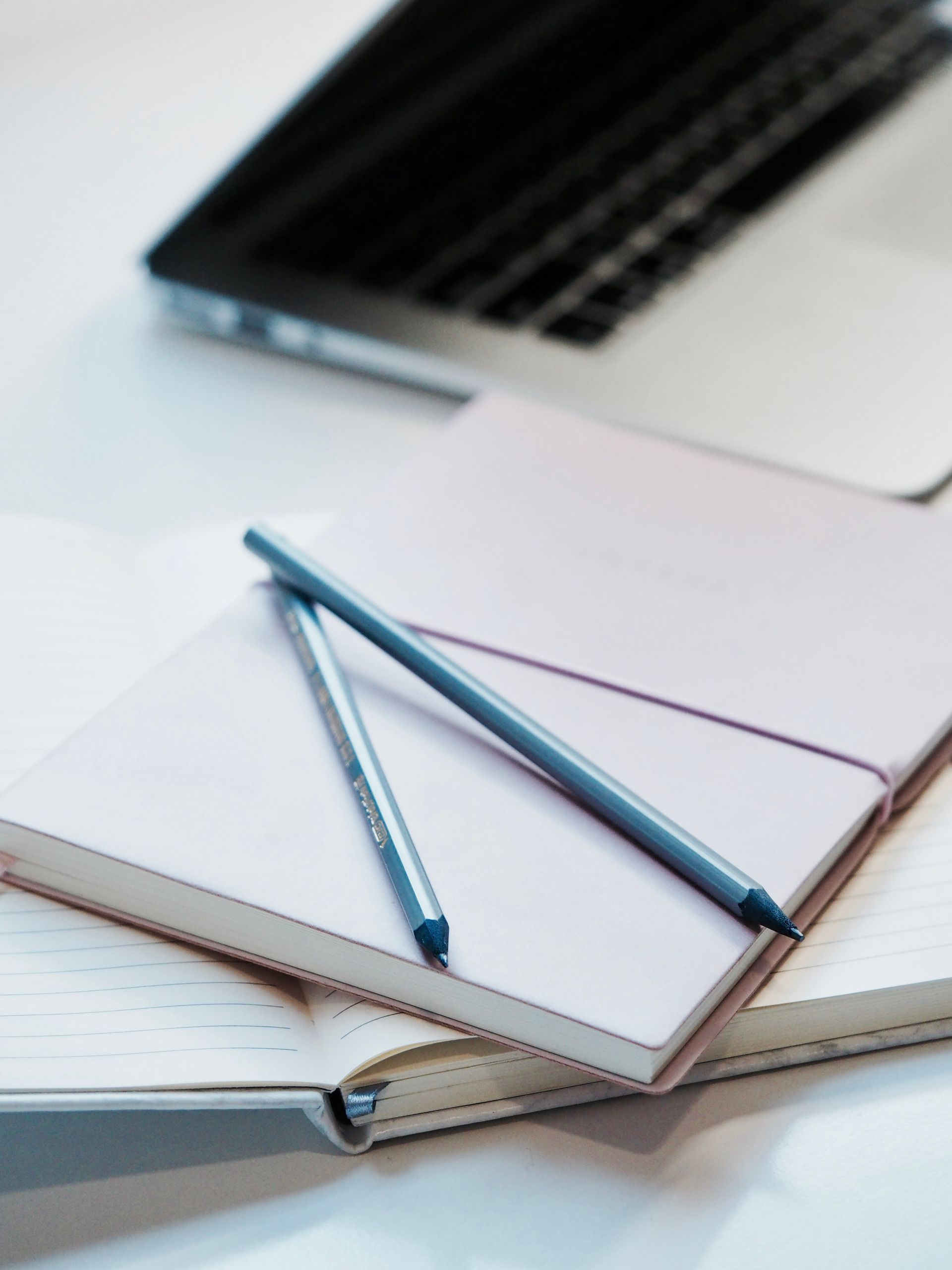 A tidy workspace with notebooks, pencils, and a laptop for productivity.